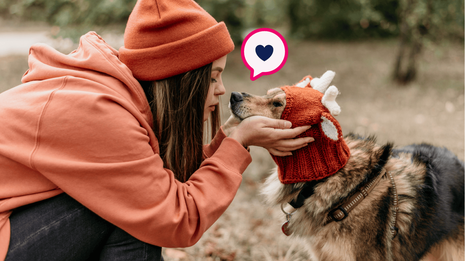 A pet parent kissing their dog while on a walk in the fall.